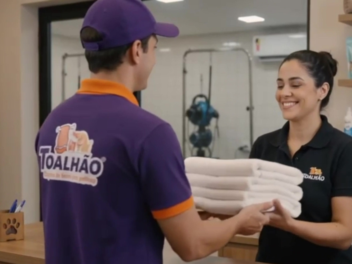 Entregador do Toalhão passando o lote de toalhas limpas para a atendente do petshop